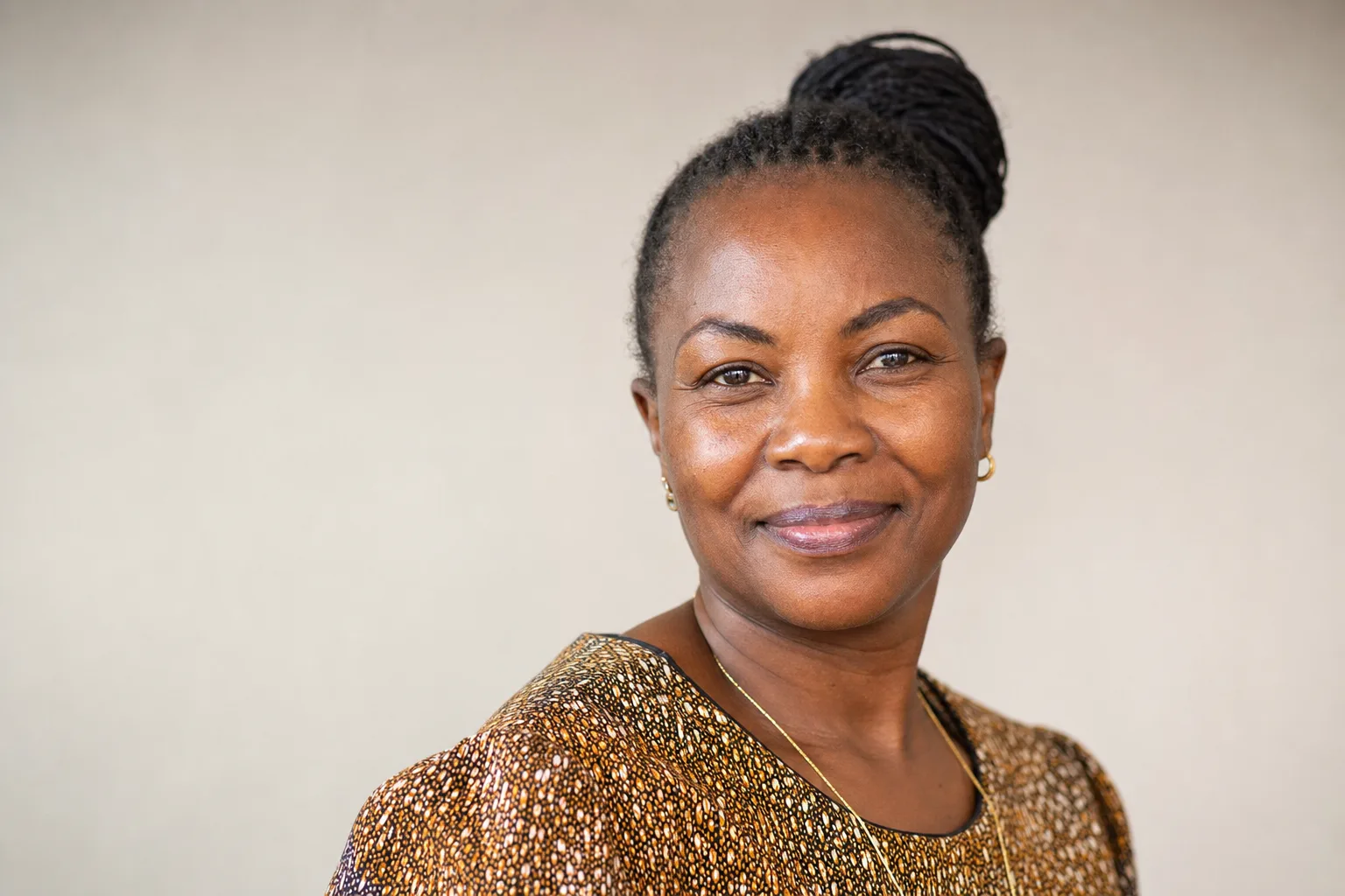 Radiant Black African woman in her 40s with firm, glowing deep brown skin smiling confidently in soft natural light