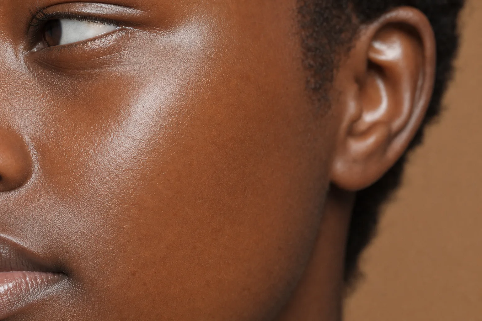 Close-up of smooth, even, naturally glowing deep brown skin on a Black African woman's cheek